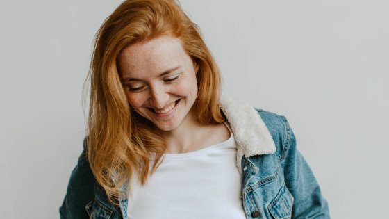 Valeria Ushakova/Canva Mulher sorrindo olhando para baixo