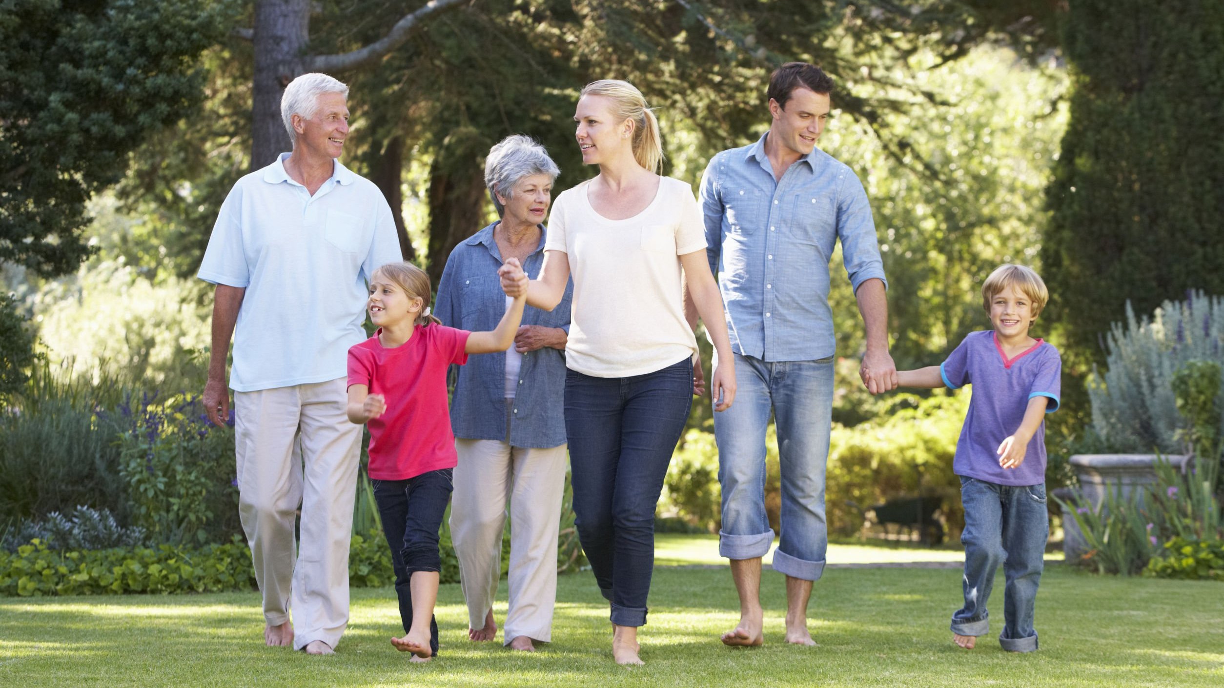 Família feliz, todos sorrindo, caminhando em parque.