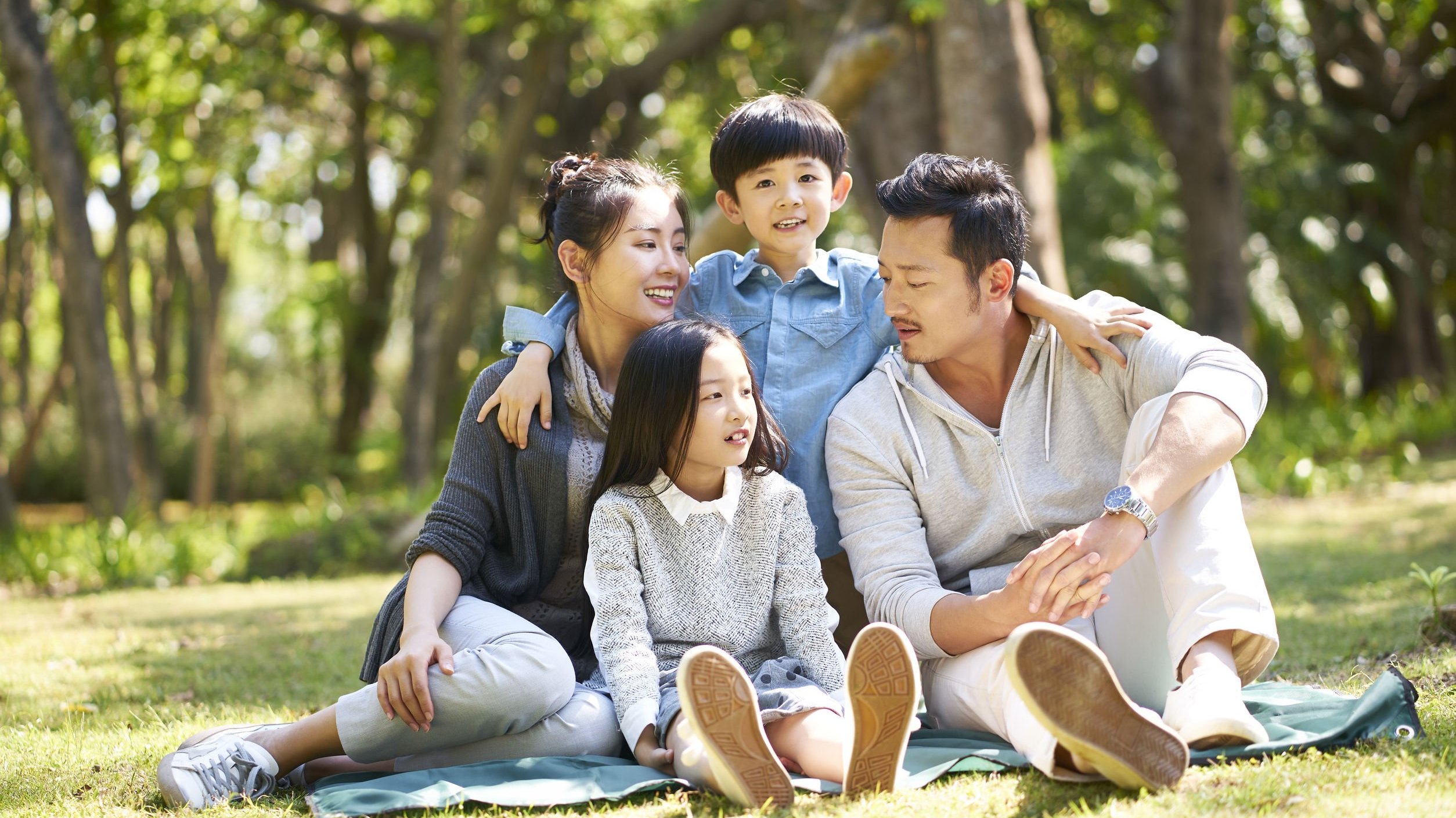 Família asiática em parque.