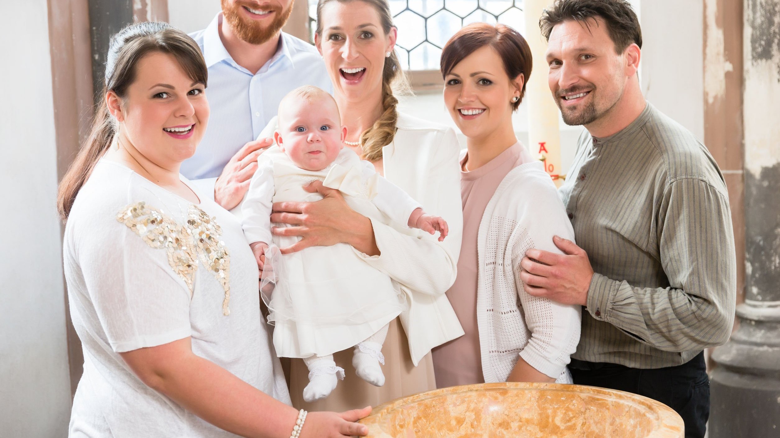 Família sorrindo em batismo. Madrinha segurando neném.