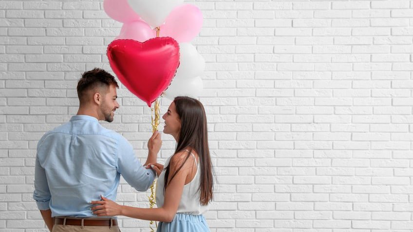 Casal segurando balões de coração