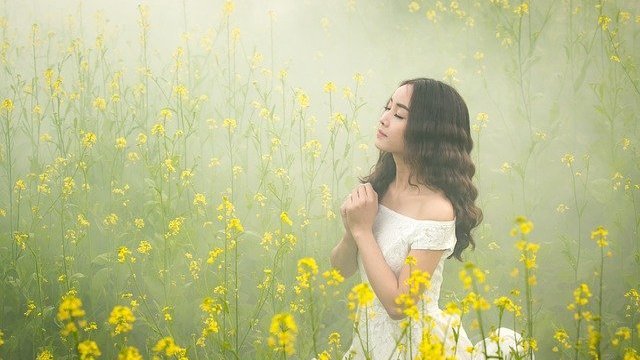 Menina orando em campo de flores