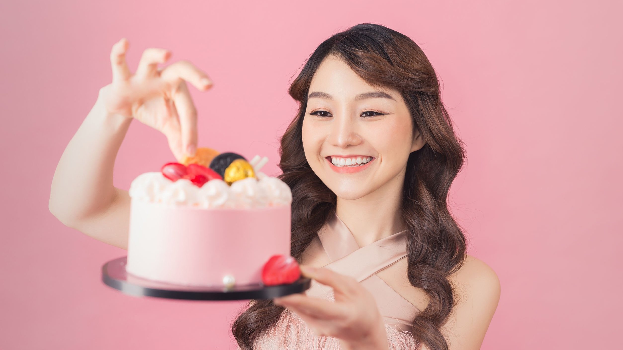 Menina sorrindo, segurando bolo de aniversário.