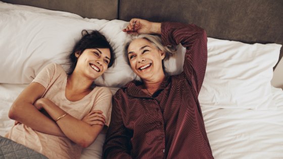 Duas mulheres deitadas na cama sorrindo
