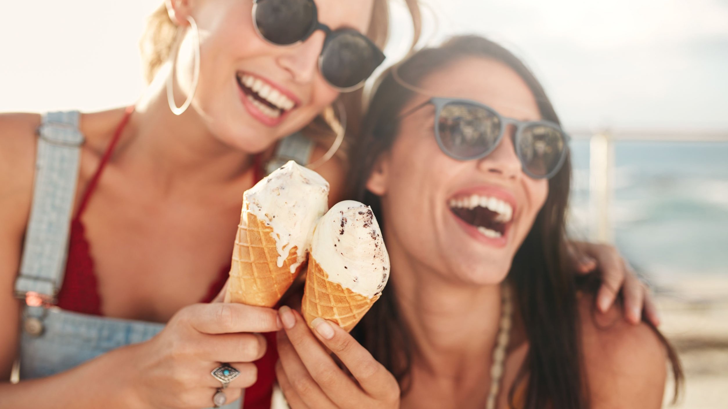 Mulheres sorrindo e segurando sorvete.