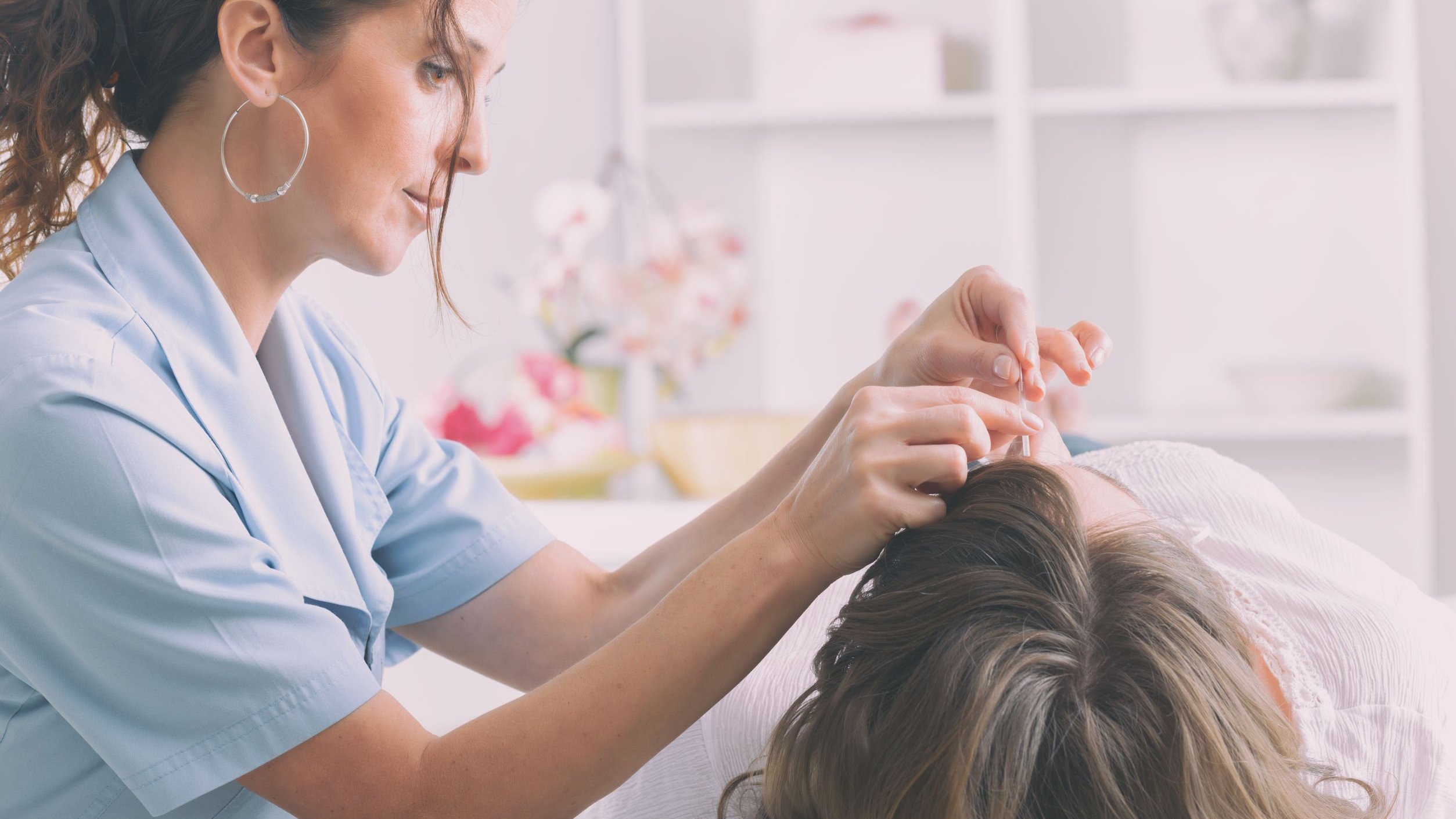 Mulher fazendo sessão de Acupuntura em cliente.