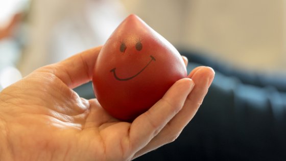 Pessoa segurando uma gota de sangue com rostinho feliz