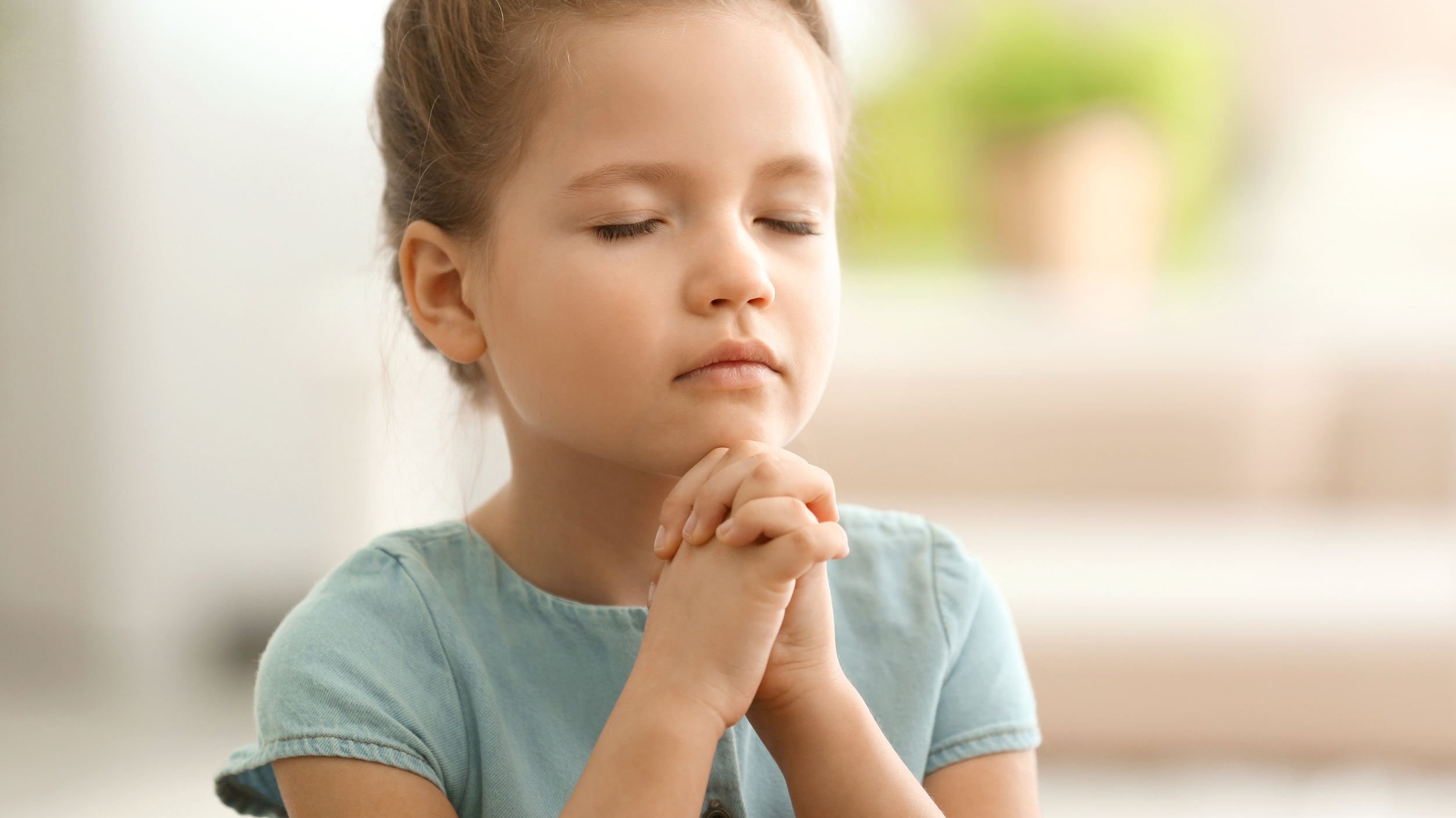Menina de olhos fechados orando.