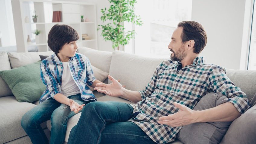 Pai e filho conversando em sofá