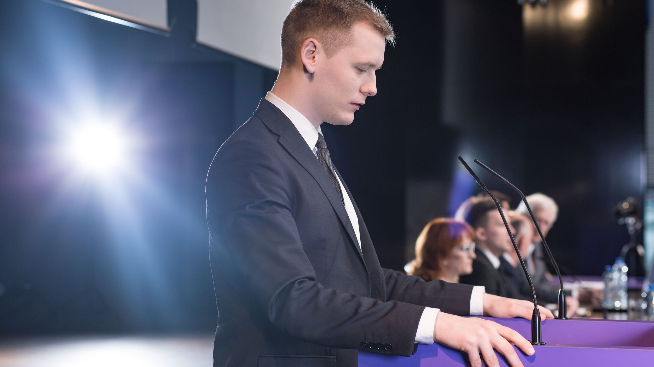 Estudante formando em palco, fazendo discurso de agradecimento.