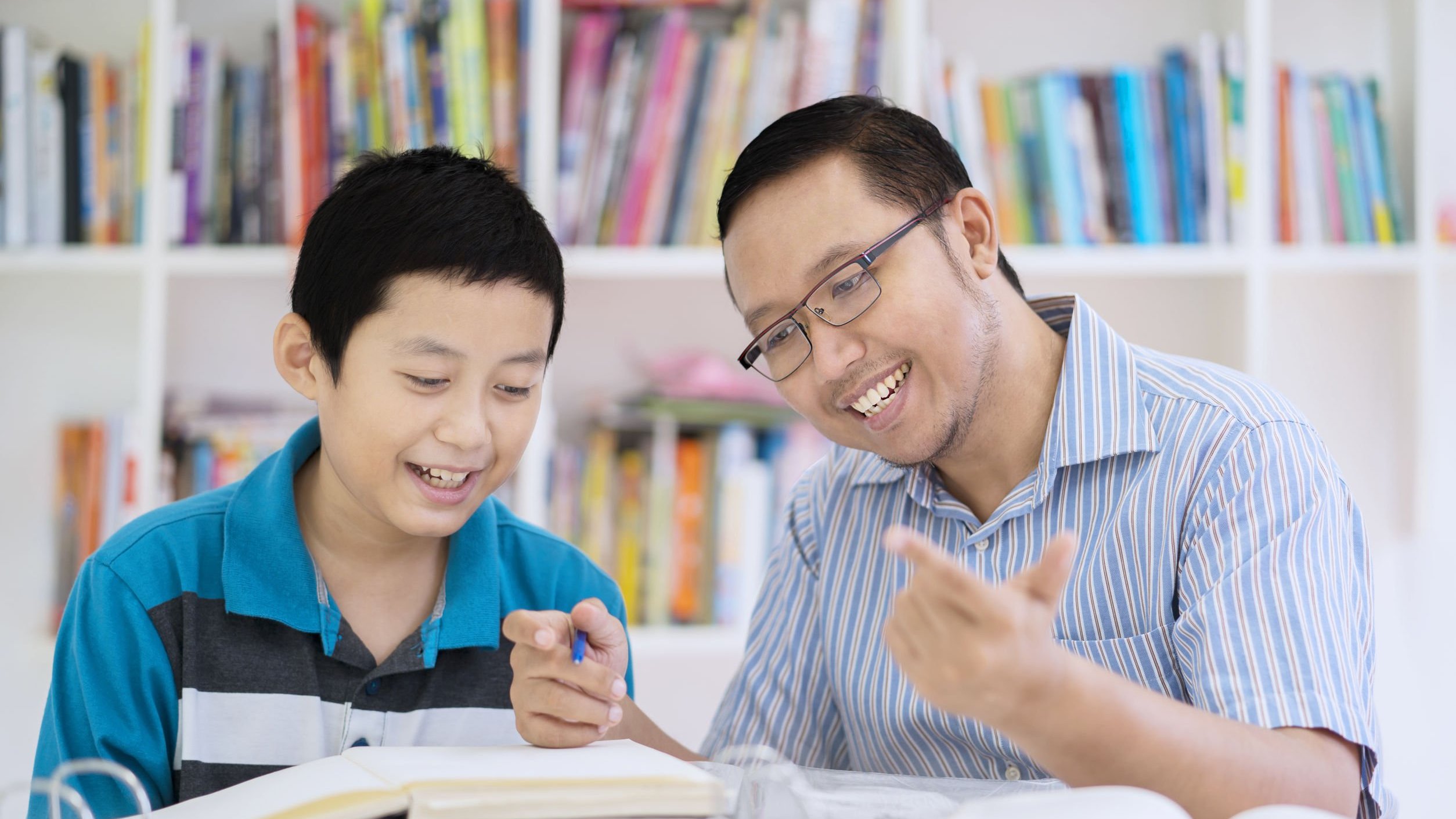 Pai e filho estudando, sorrindo.