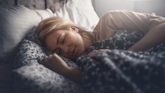 Mulher deitada na cama de olhos fechados