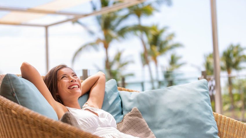 Mulher sorrindo deitada em sofá com almofadas