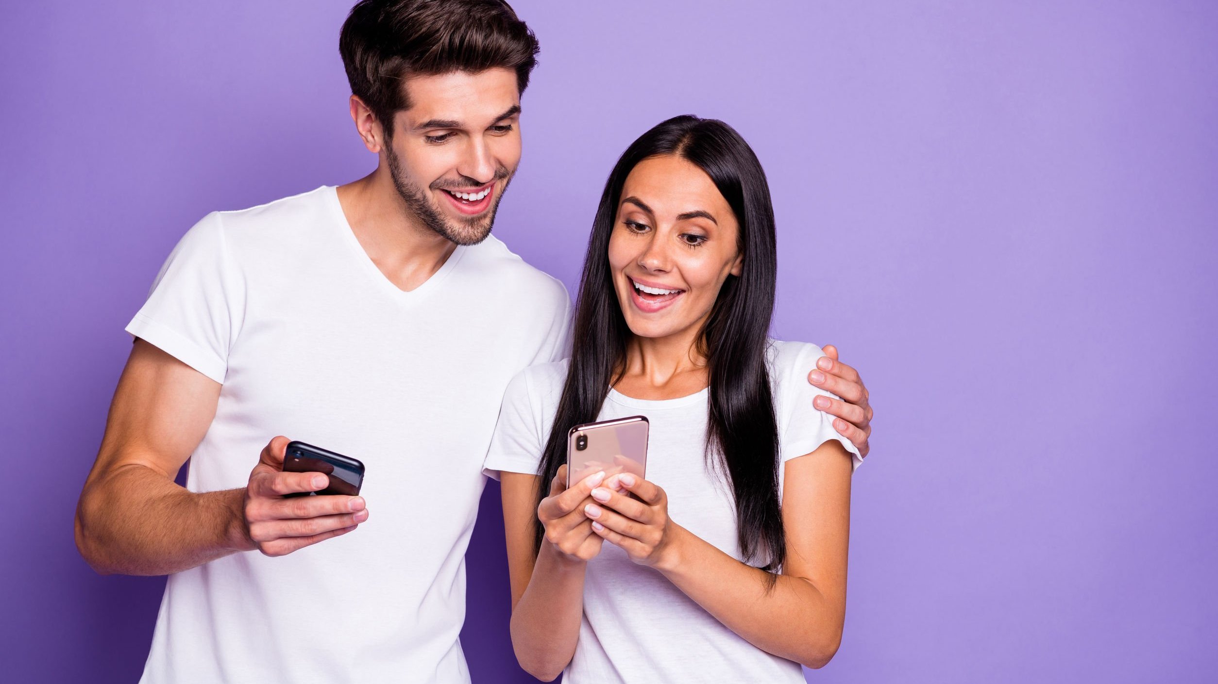 Homem e mulher, amigos, olhando para celular e sorrindo.