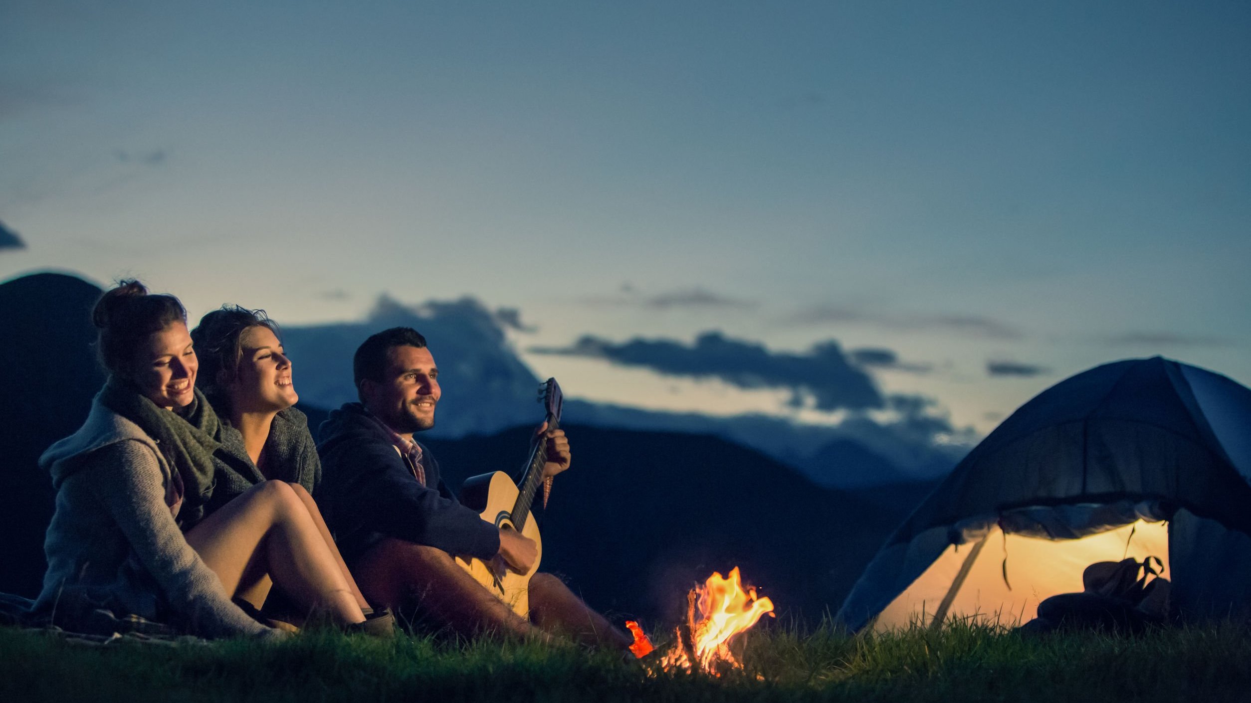 Amigos sentados, acampando.