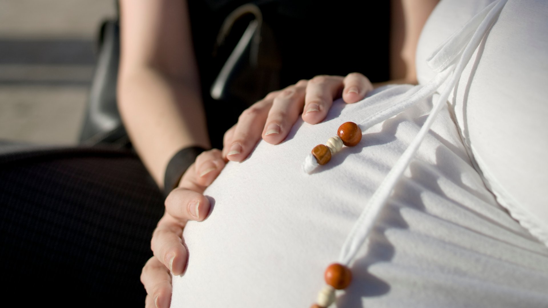 Mulher com as mãos na barriga de uma outra mulher grávida