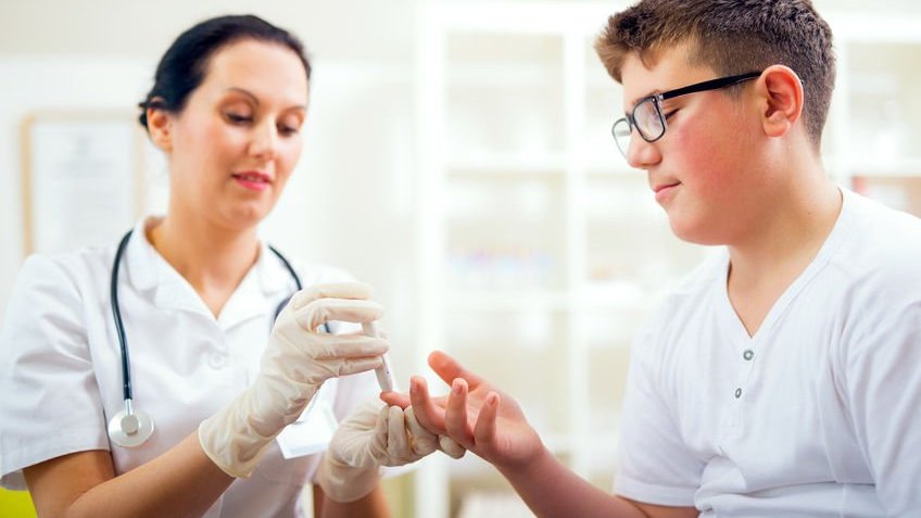 Médica medindo nível de glicose de garoto