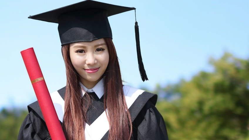 Menina asiática com beca de formatura e diploma