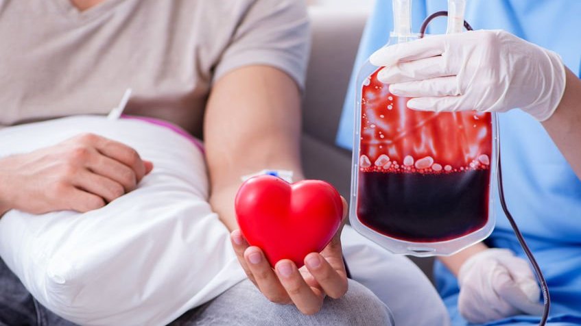 Enfermeiro segurando bolsa de sangue e doador segurando coração de brinquedo