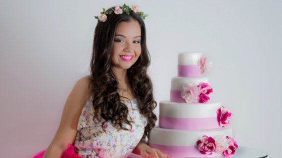 Debutante sorrindo ao lado de bolo de aniversário