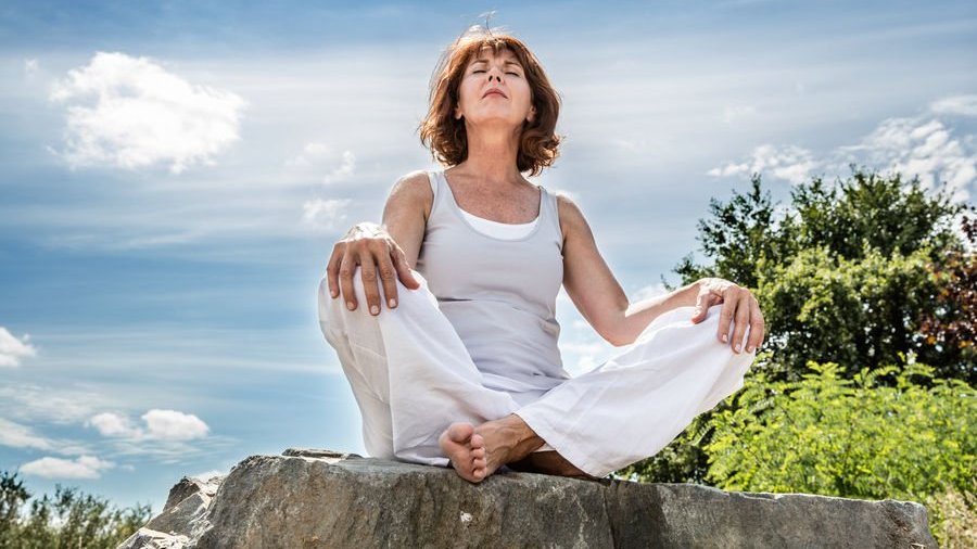 Mulher meditando em pedra