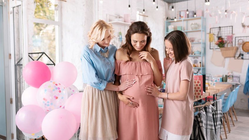Amigas tocando barriga de mulher grávida em chá de bebê