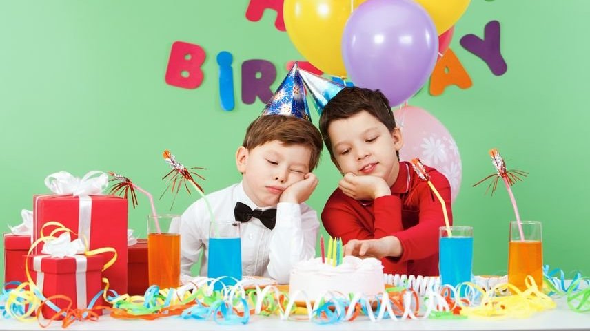 Duas crianças entediadas em frente a bolo de aniversário