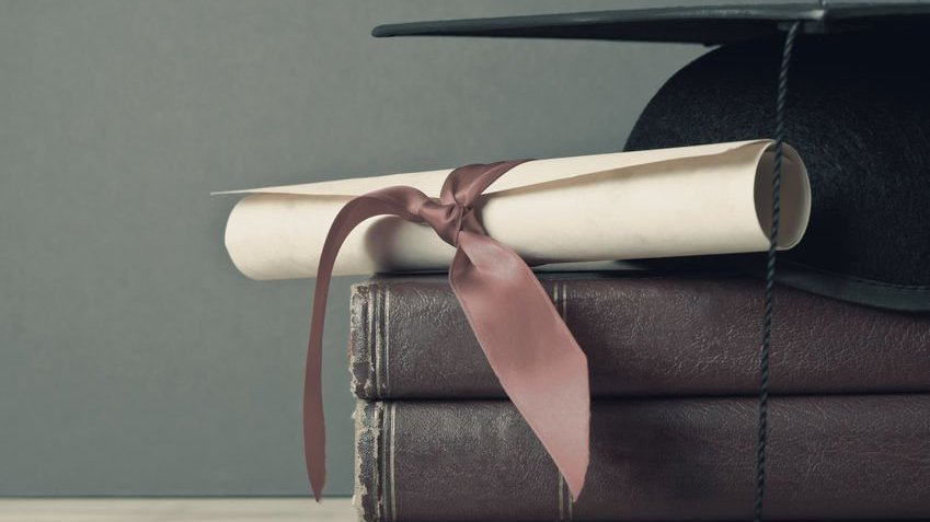 Livros, diploma e chapéu de formatura