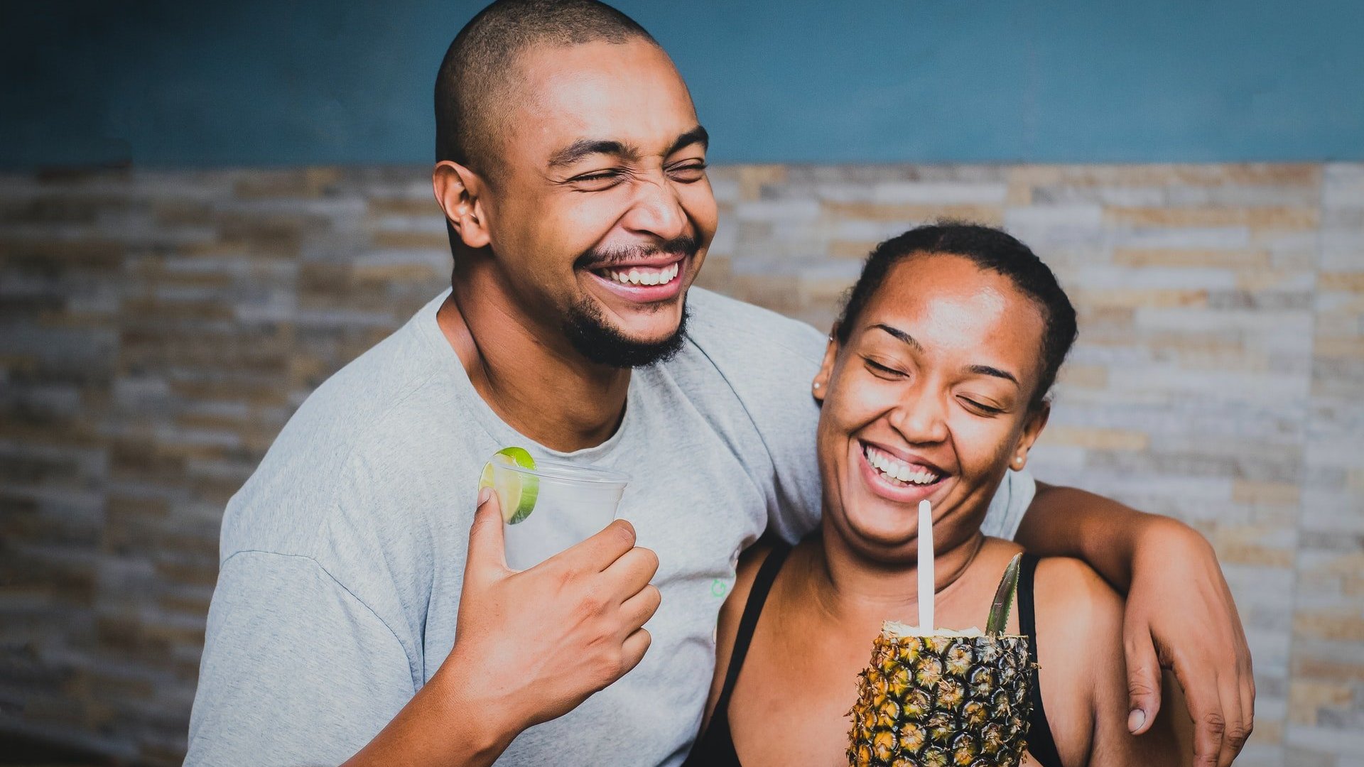 Homem e mulher negros sorrindo abraçados.