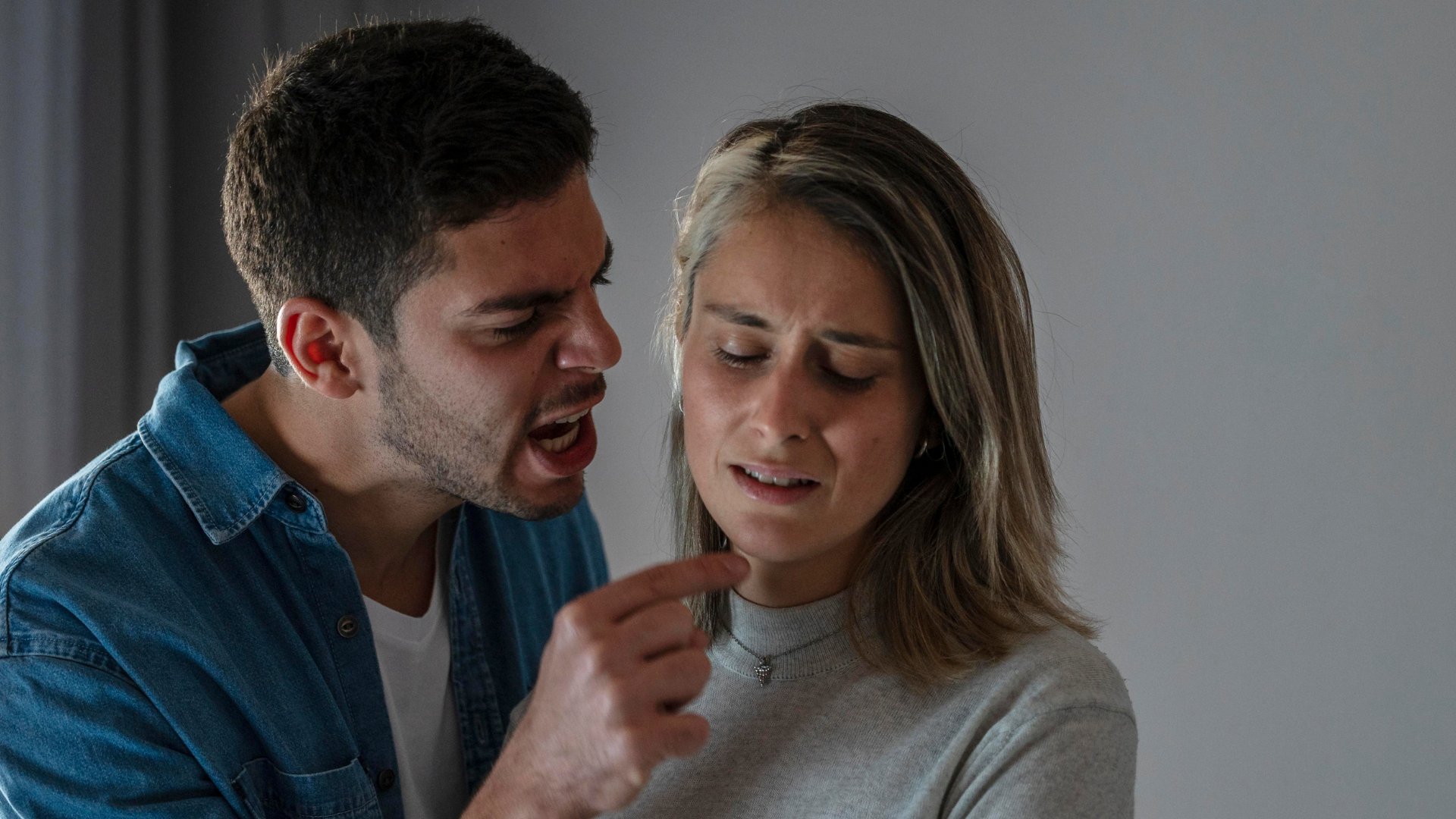 Um homem com raiva apontando o dedo para uma mulher triste/abatida.