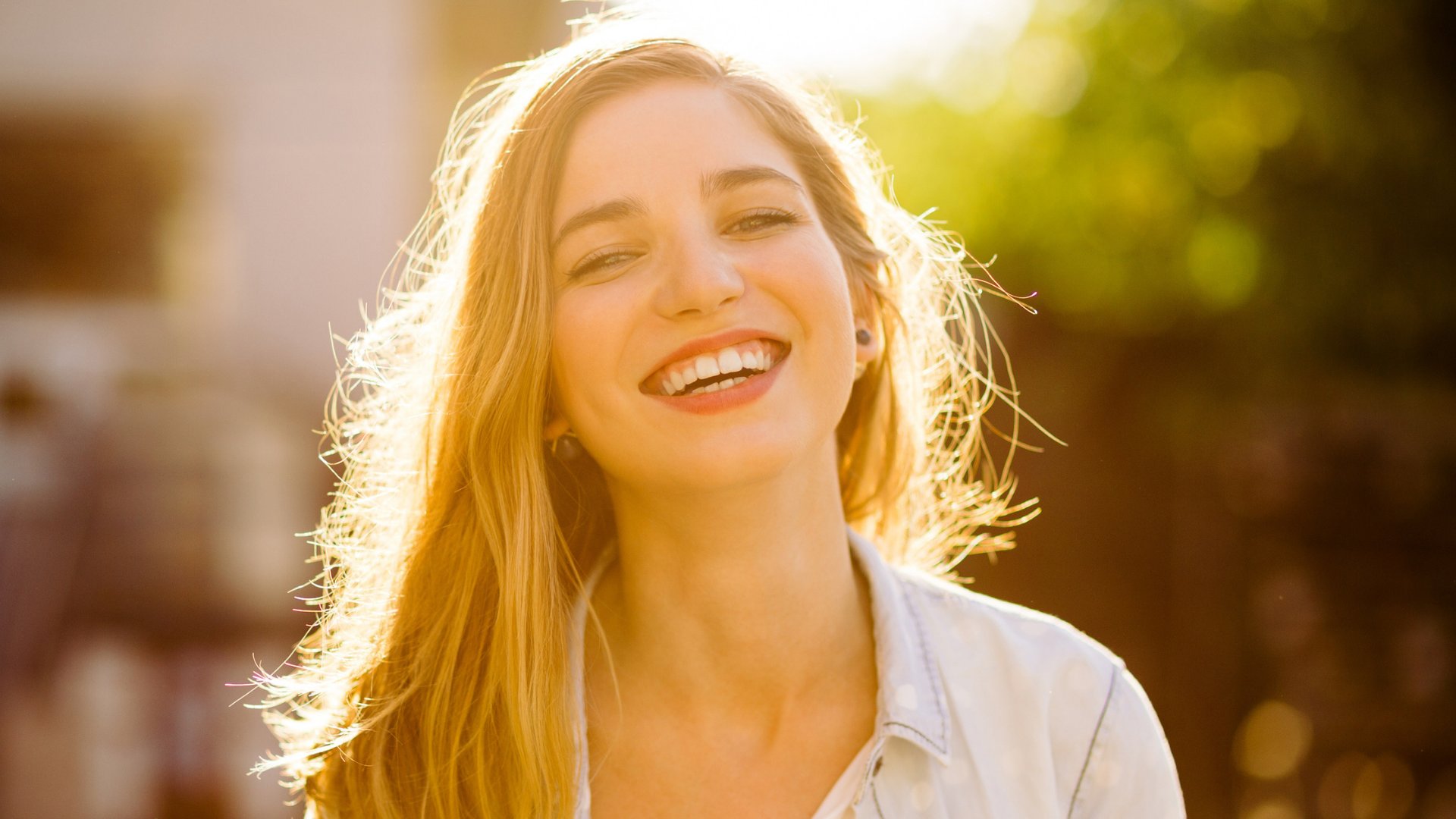 Uma mulher loira sorrindo com uma luz solar de fundo