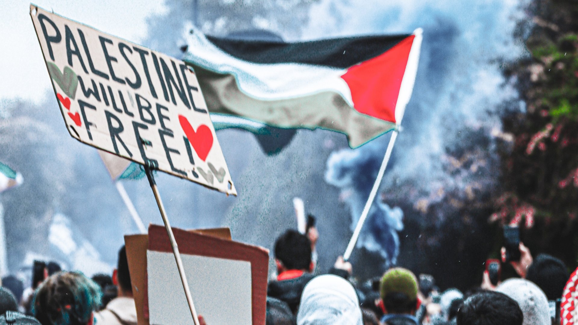 Manifestantes pró-Palestina. Um deles segura uma placa que diz palestine will be free!
