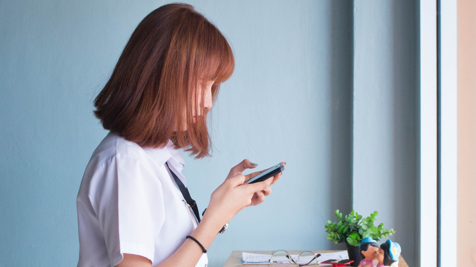 Uma mulher asiática de cabelos ruivos olhando um celular fixamente