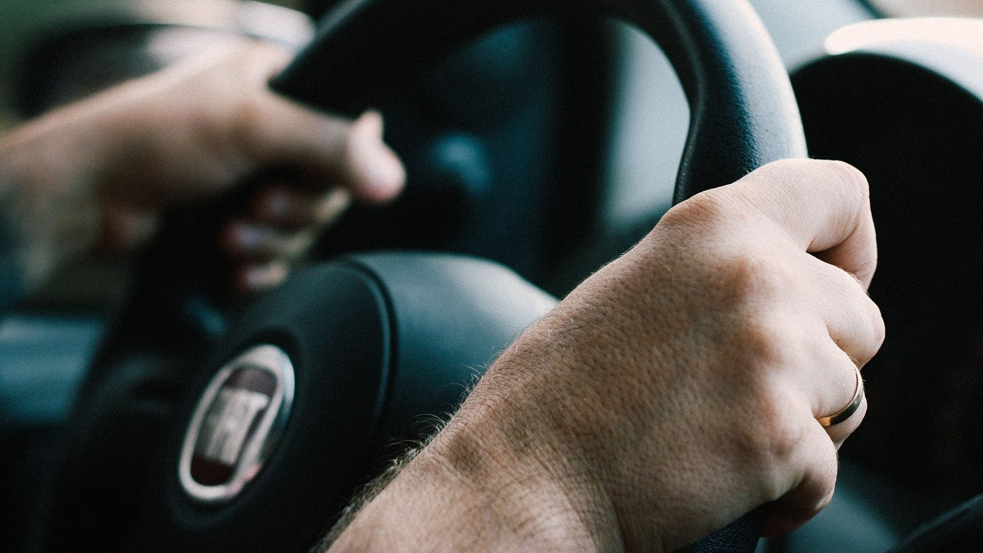 Duas mãos segurando um volante de um carro