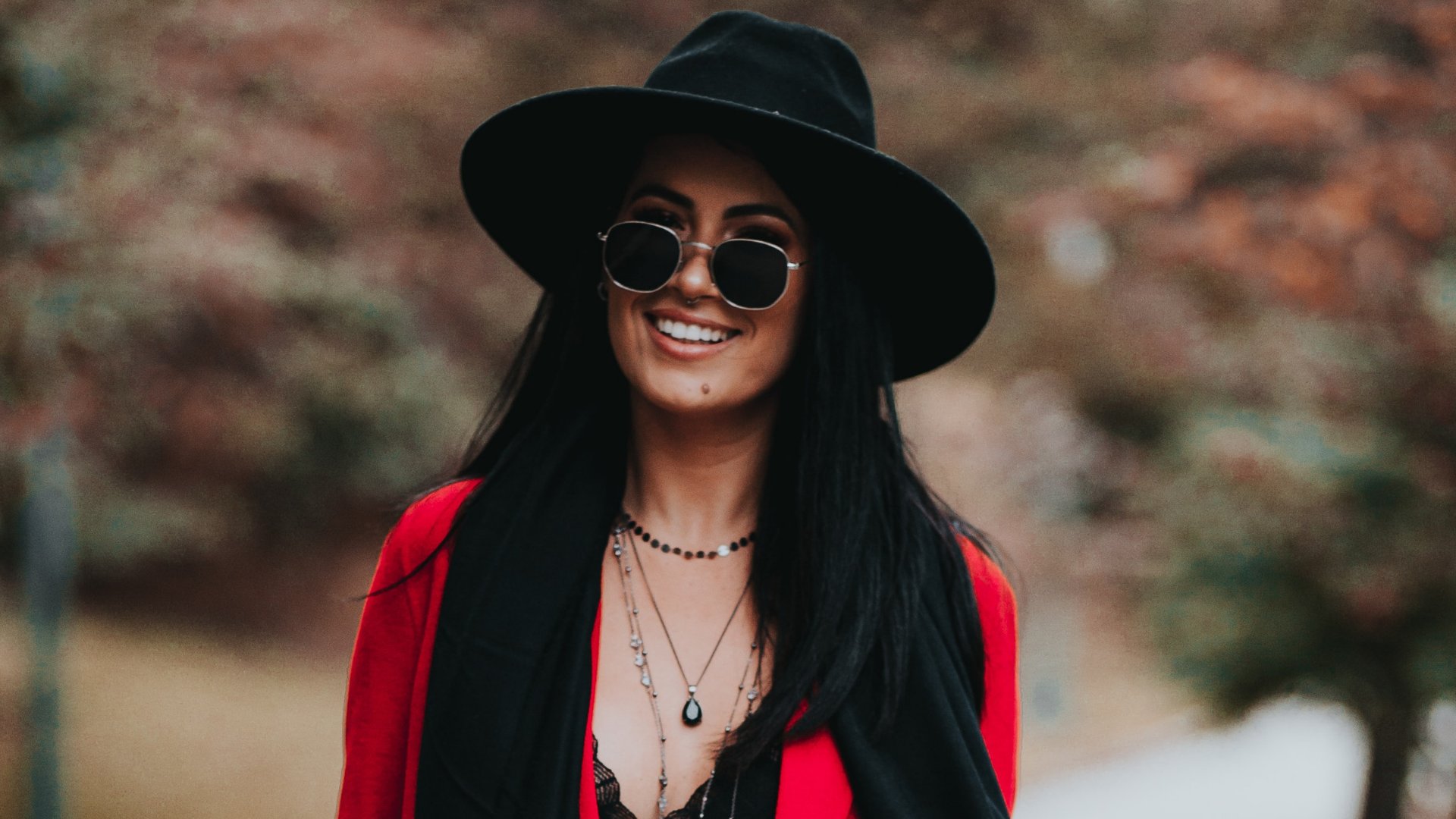 Uma mulher de chapéu preto e óculos escuros sorrindo