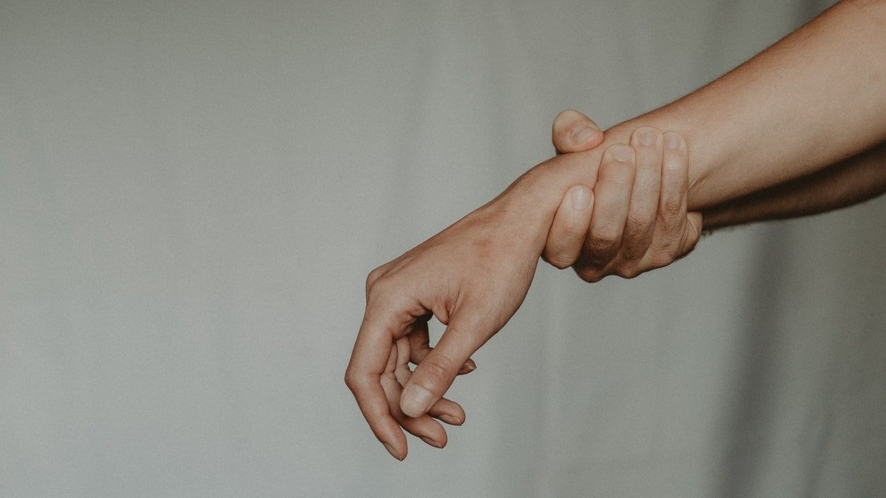 Uma mão masculina segurando firmemente um braço de uma mulher