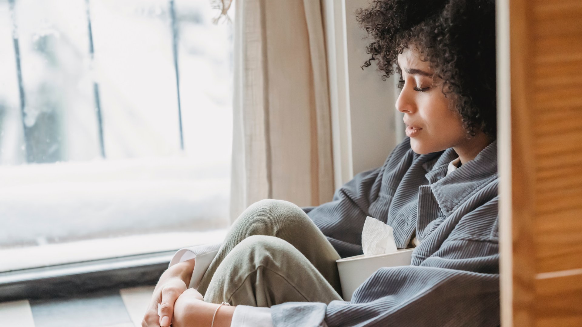 Liza Summer / Pexels / Canva / Mensagens Com Amor Uma mulher negra sentada próxima à janela. No seu colo, um rolo de papel higiênico.
