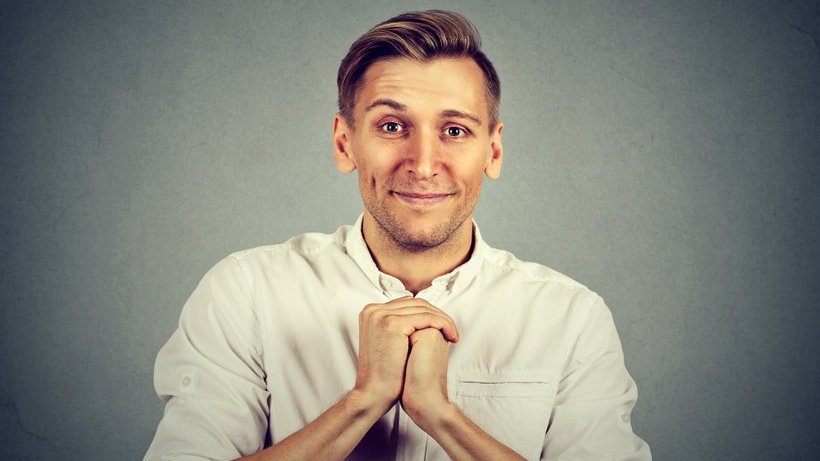 Homem branco com expressão amigável e mãos juntas.