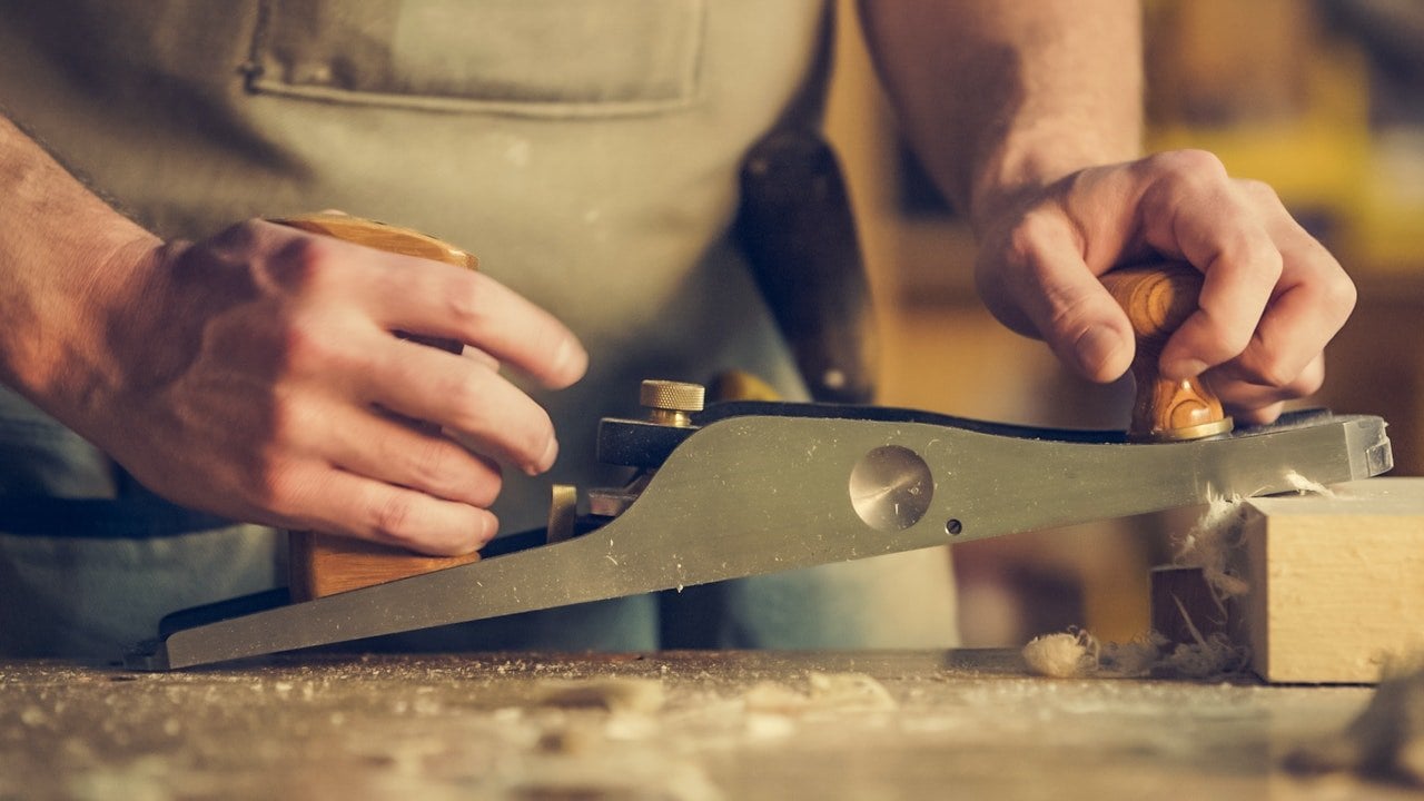 Um homem manipulando uma ferramenta de carpintaria.