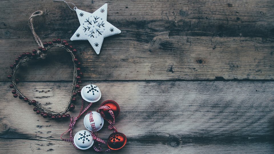 Itens de adorno natalinos: uma guirlanda e uma estrela, postos sobre uma superfície de madeira.