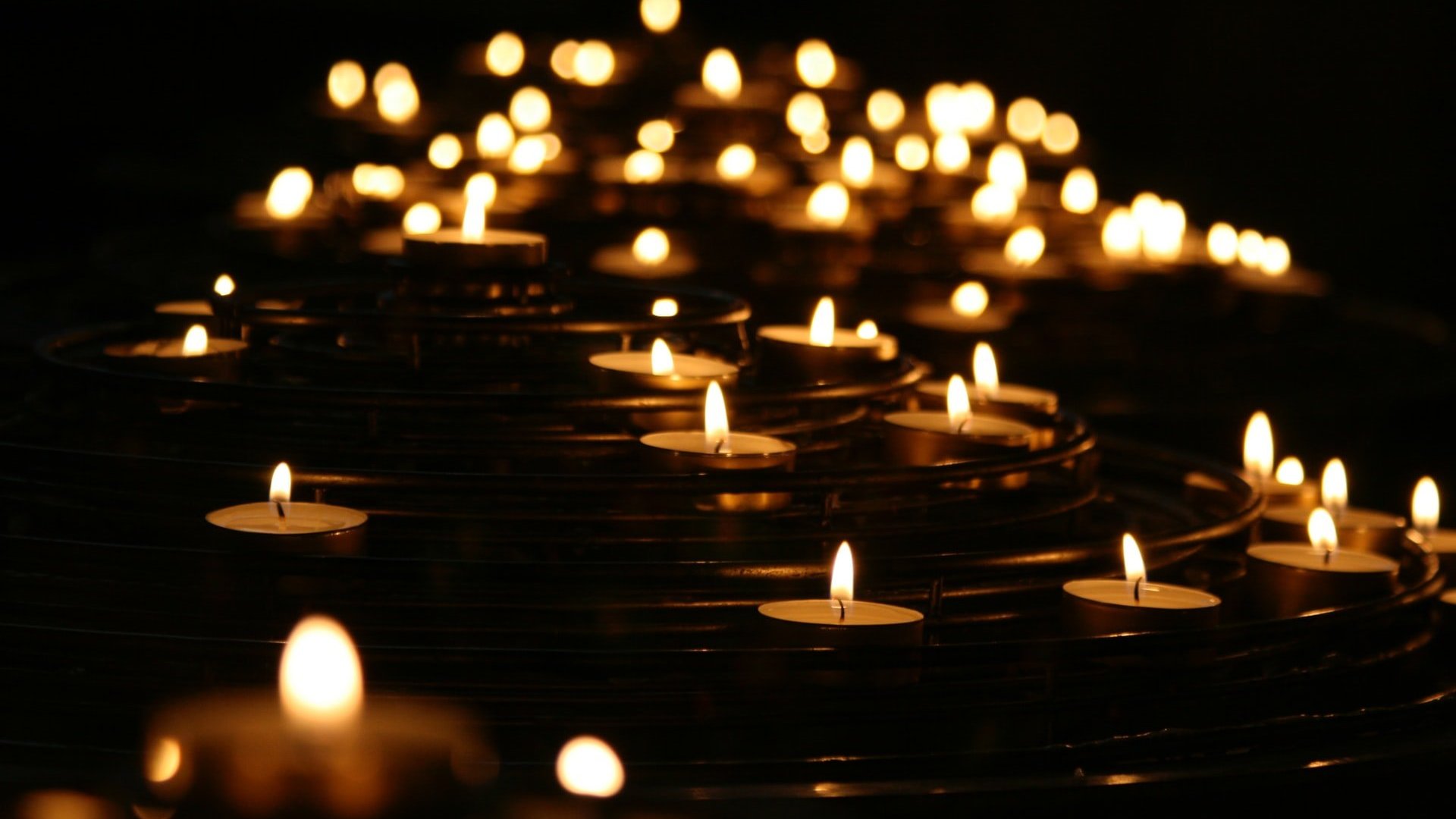 Várias pequenas velas acesas dispostos no escuro