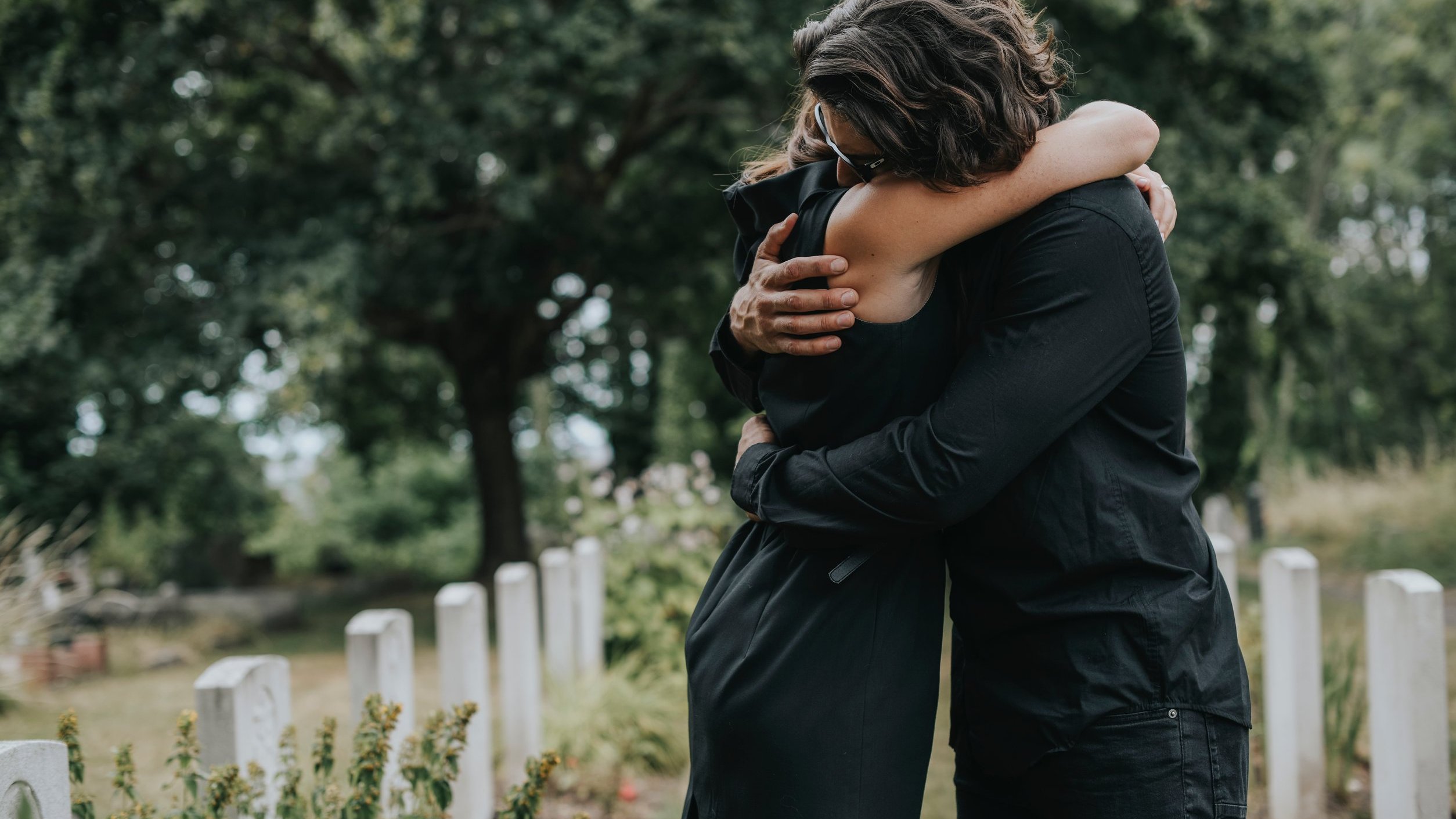 Homem abraça mulher em um cemitério