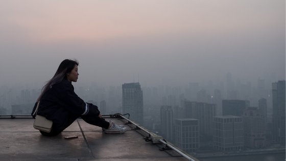 Mulher sentada em topo de prédio refletindo
