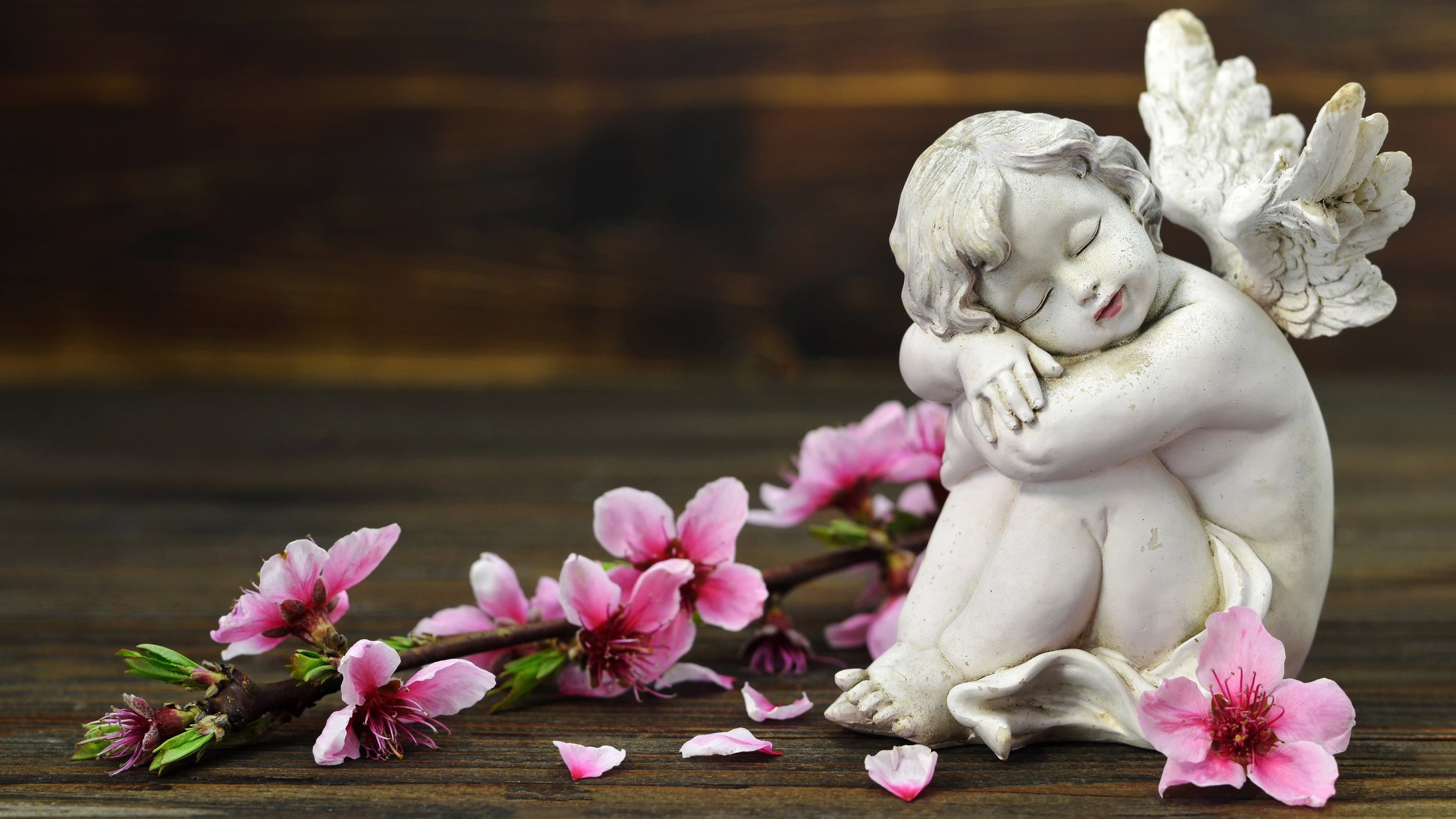 Estátua de um anjo sentada em volta de flores