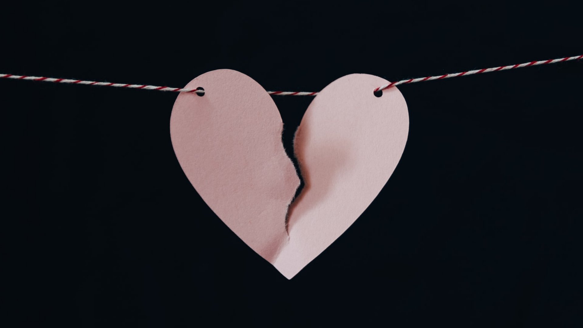 Um coração de papel rasgado pendurado no meio pendurado num varal de barbante.