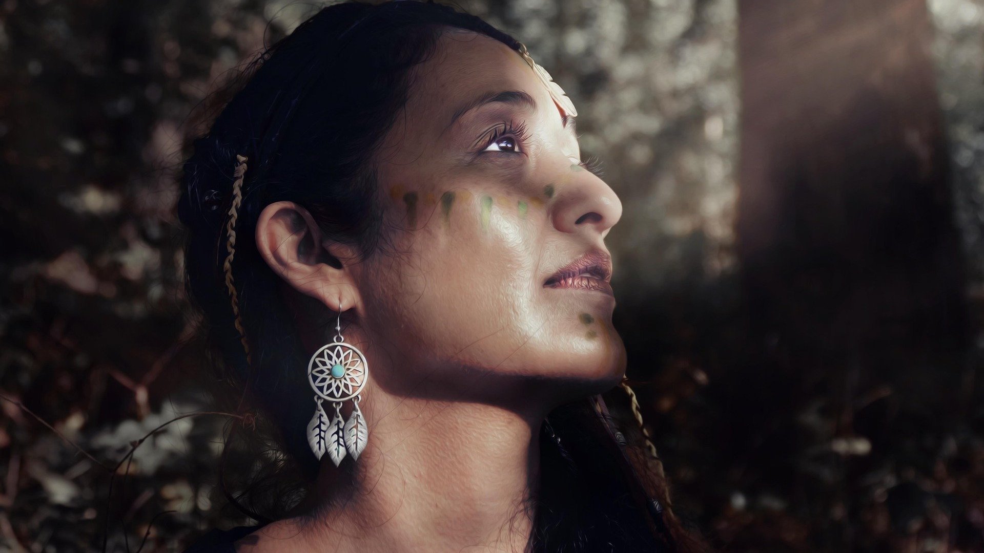 Uma mulher morena com cocar indígena, pintura arquetípica indígena e brincos .