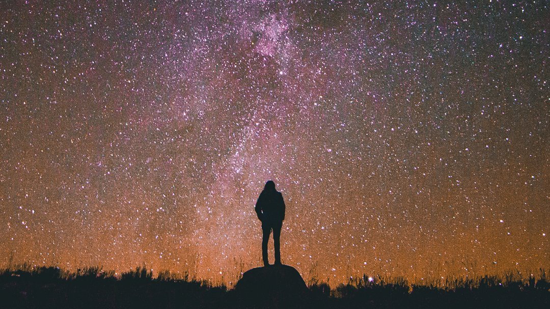 Um homem contemplando um céu estrelado.