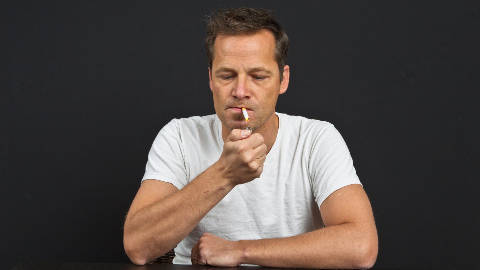 Um homem acendendo um cigarro.