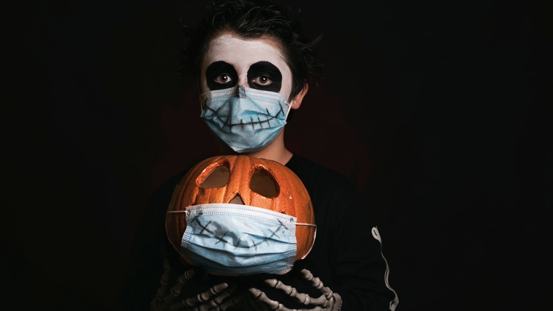 Um garoto segurando uma abóbora que usa uma máscara.