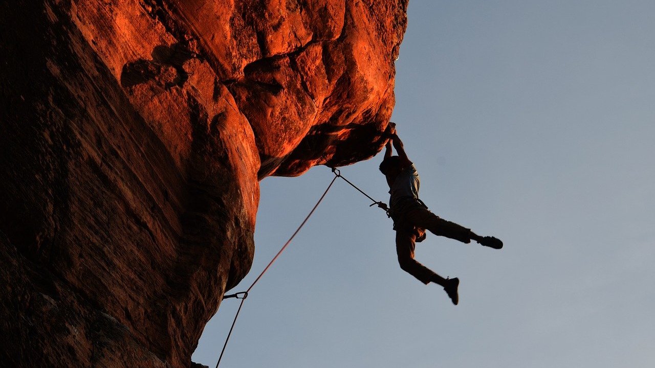 Atleta de escalada pendurado em rocha gigante